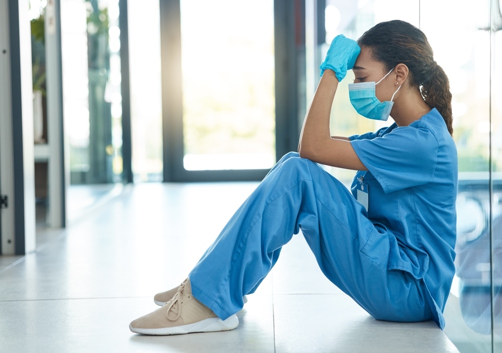 Exhausted healthcare worker sitting on the floor in a hospital hallway
