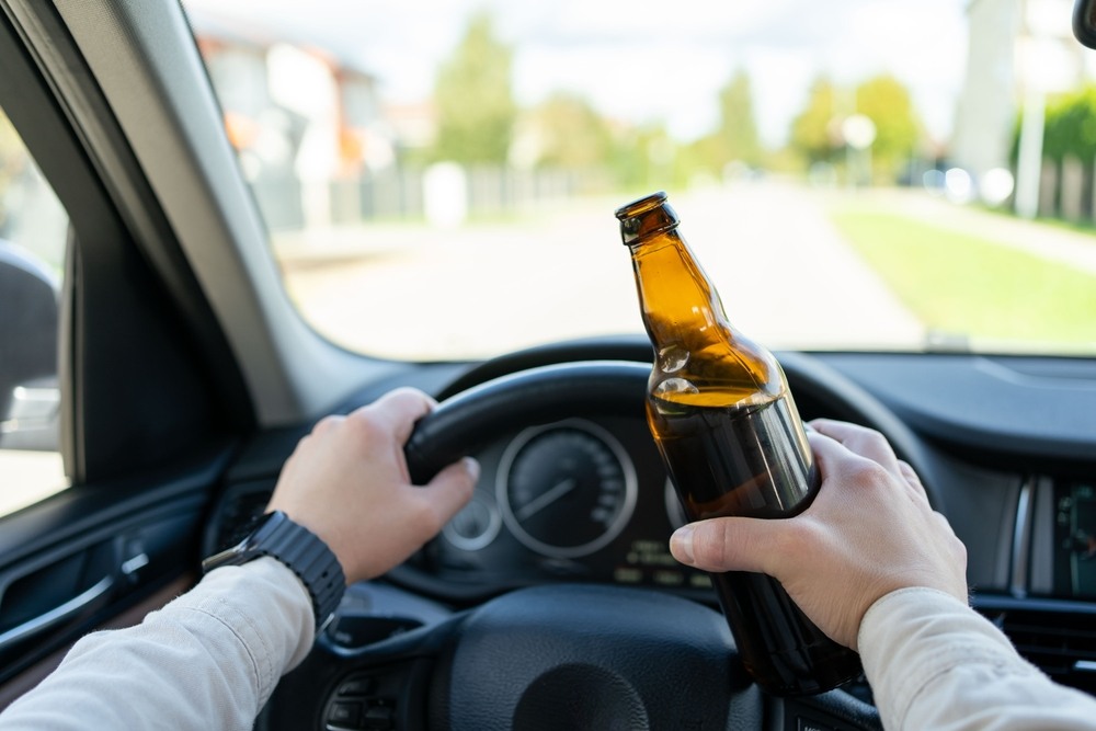 Man driving while holding a beer bottle, representing an Appleton drunk driving accident case