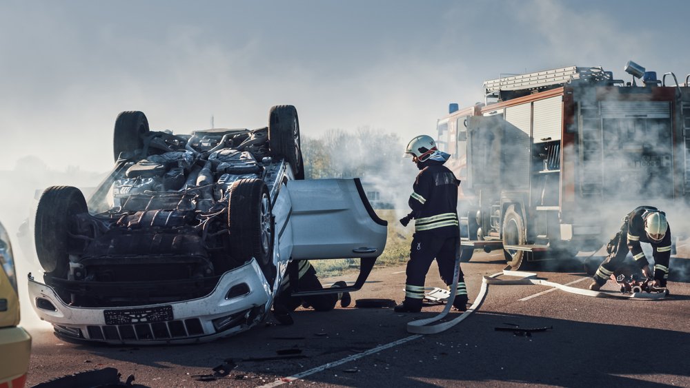 Firefighters responding to an overturned vehicle after a severe car accident that caused a catastrophic injury
